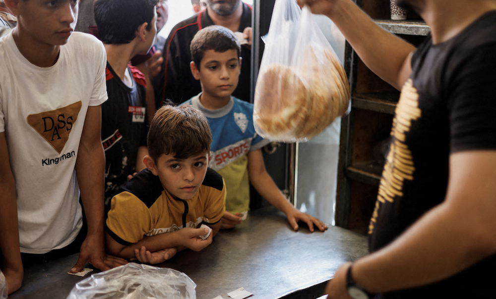 Palestinians wait to buy bread outside a bakery, amid the ongoing conflict between Israel and Palestinian Islamist group Hamas, in Khan Younis in the southern Gaza Strip October 14, 2023. (REUTERS/File)
