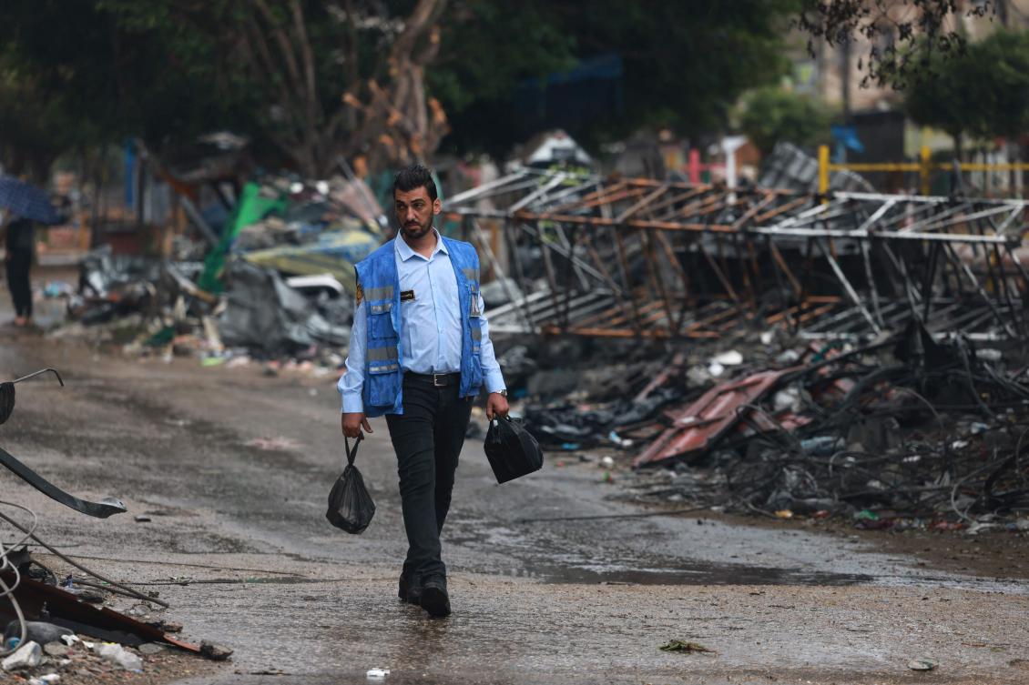 A Palestinian man wearing a United Nations blue vest walks past the debris following the Israeli bombardment of Rafah in the southern Gaza Strip on Nov. 14, 2023. (AFP)