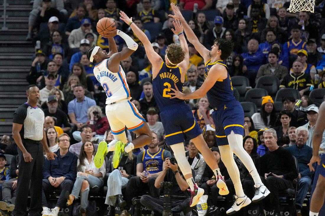 Oklahoma City Thunder guard Shai Gilgeous-Alexander, left, scores against Golden State Warriors guard Brandin Podziemski, middle, and forward Dario Saric during the second half of an NBA basketball game in San Francisco. (AP)