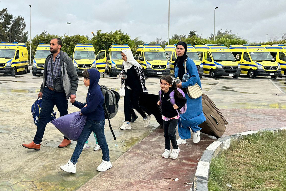 Passengers fleeing the war-torn Gaza Strip arrive to the Egyptian side of the Rafah border crossing with the Palestinian territory. (File/AFP)