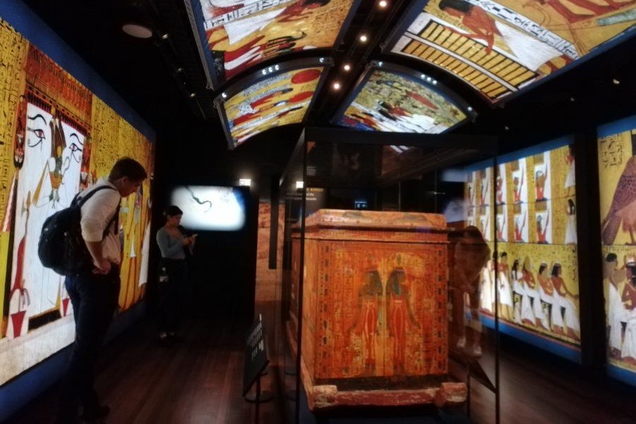 The outer coffin of Sennedjem, the artisan who worked on Ramses’ tomb, surrounded by projected paintings from his tomb, depicting the journey through the Underworld. (ArtsHub)