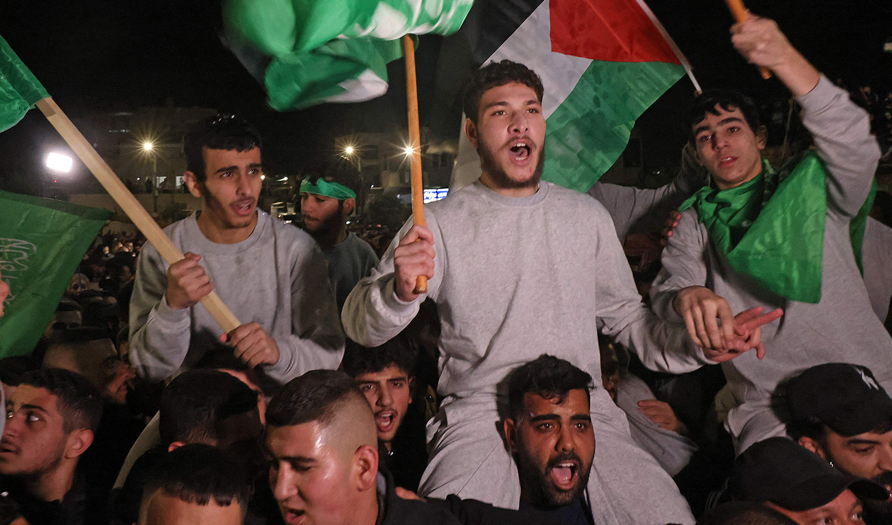 Palestinian prisoners (wearing grey jumpers) cheer after being released from the Israeli Ofer military facility in Baytunia near the city of Ramallah in the occupied West Bank in exchange for hostages freed by Hamas in Gaza, on November 24, 2023. (AFP)