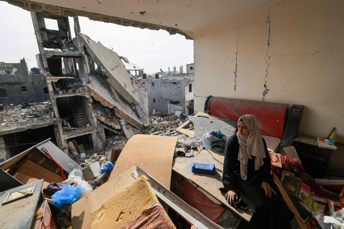A Palestinian woman sits on debris in her damaged apartment in the Khezaa district on the outskirts of the southern Gaza Strip city of Khan Yunis, following weeks of Israeli bombardment, as a truce between Israel and Hamas entered its second day on November 25, 2023. (AFP)