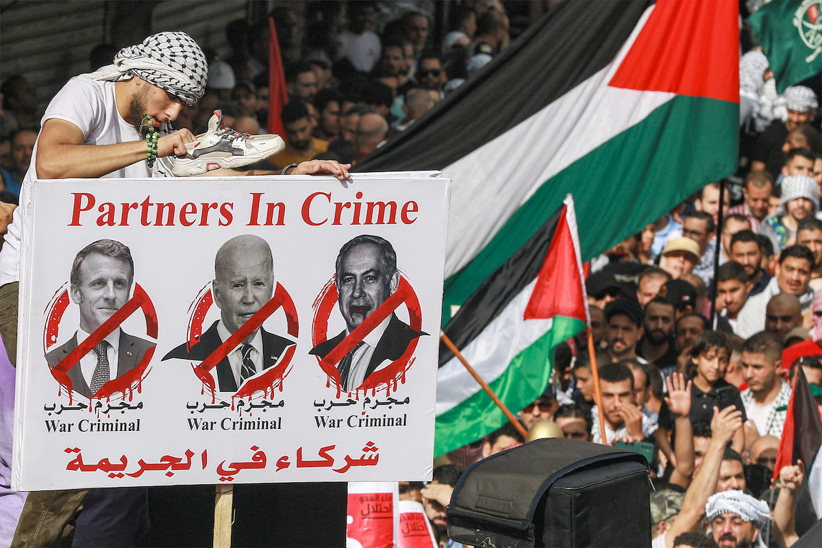 Protesters raise a sign condemning French President Emmanuel Macron, US President Joe Biden, and Israeli PM Benjamin Netanyahu during a rally in solidarity with Palestinians in the Gaza in Amman. (File/AFP)