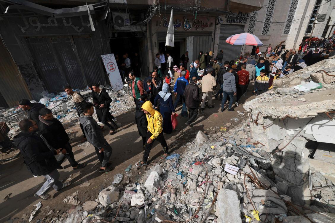 People walk past destroyed buildings in the southern Gaza Strip city of Khan Yunis on November 28, 2023. (AFP)