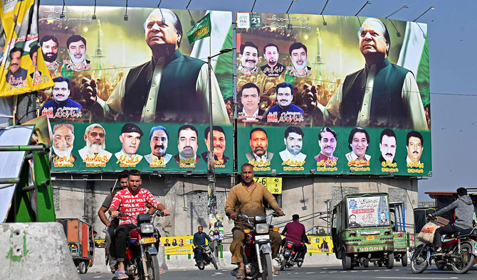 People ride past large banners of Pakistan's former Prime Minister Nawaz Sharif displayed along a street ahead of his arrival in Lahore in October 2023. (AFP/File)