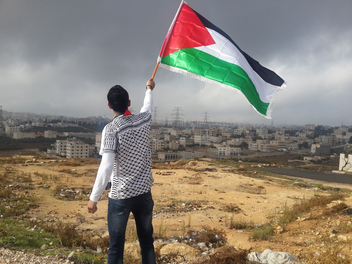 A senior CIA official posted a pro-Palestine image, showing a man waving a Palestinian flag on Facebook, last month. (Ahmed Abu Hameeda/Unsplash)