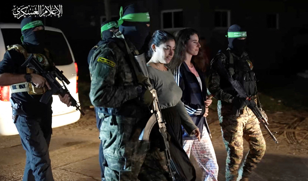 Hostages who were abducted by Hamas gunmen during the October 7 attack on Israel are handed over by Hamas militants to the International Red Cross. (Reuters)