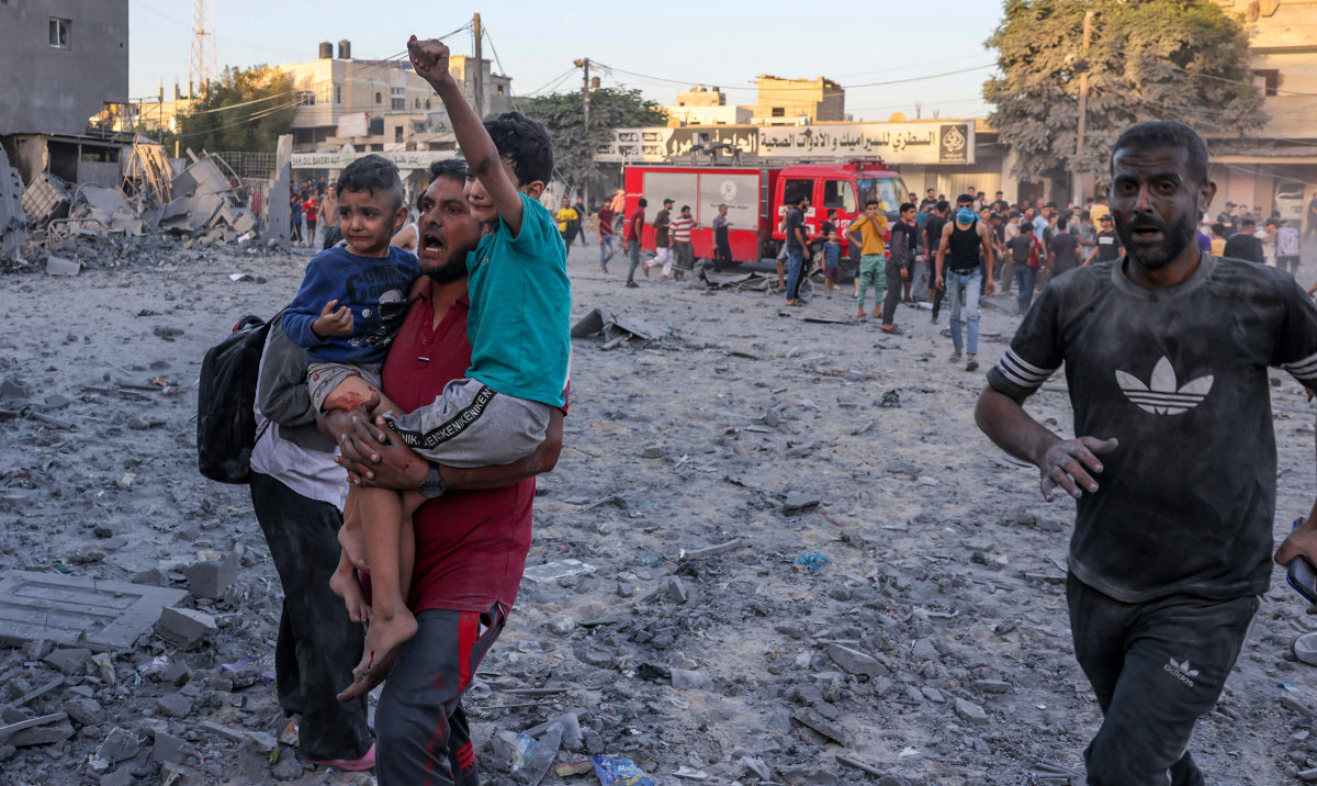 A wounded Palestinian man carries children following a strike in Rafah on the southern Gaza Strip on November 6, 2023. (AFP)