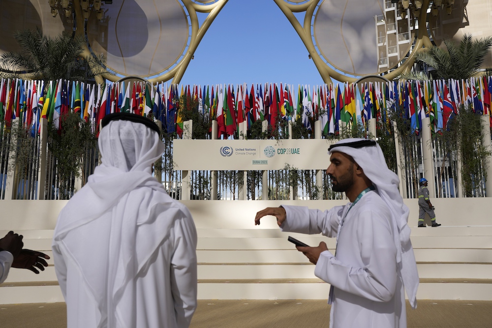 Delegates talk near a sign for the COP28 UN Climate Summit on Nov. 30, 2023 in Dubai. (AP)