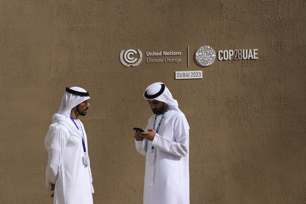 Delegates talk near a sign for the COP28 UN Climate Summit on Nov. 30, 2023 in Dubai. (AP)
