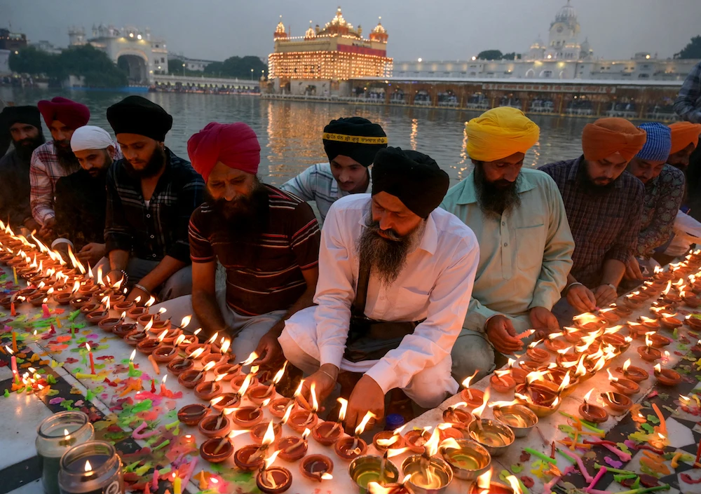 Sikh devotees light candles at the illuminated Golden Temple on the birth anniversary of Sikh Guru Ram Das, in Amritsar on October 30, 2023. (AFP)
