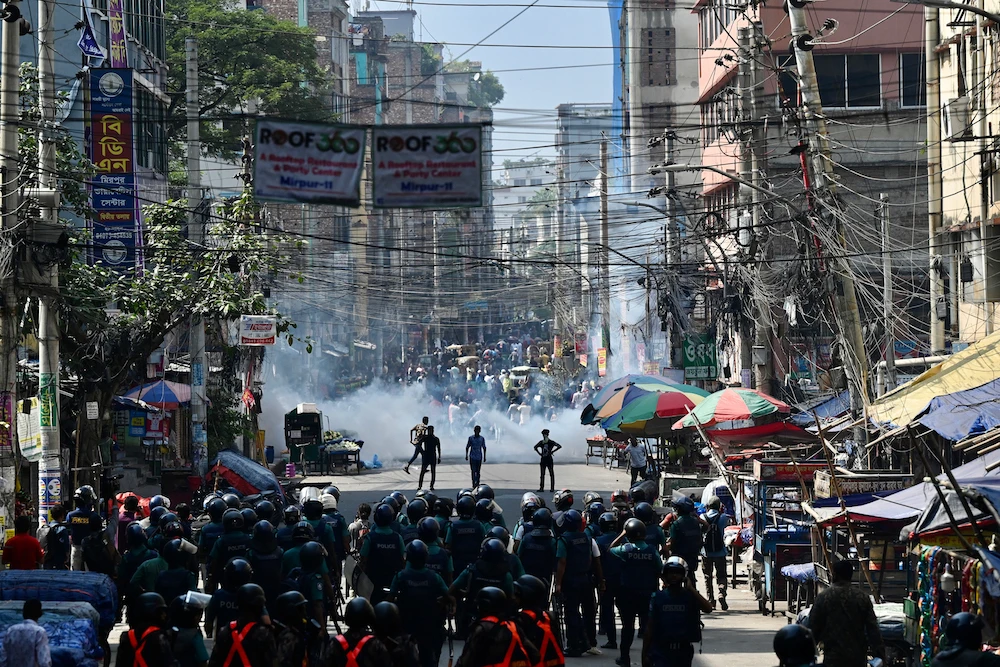 Bangladesh police (foreground) stand guard along a road during clashes with garment workers (top) protesting to demand the increase of their salaries, in Dhaka on November 2, 2023. (AFP)