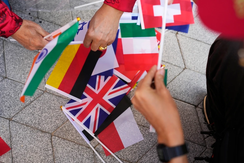A worker adjusts flags at the COP28 UN Climate Summit on Nov. 30, 2023 in Dubai. (AP)