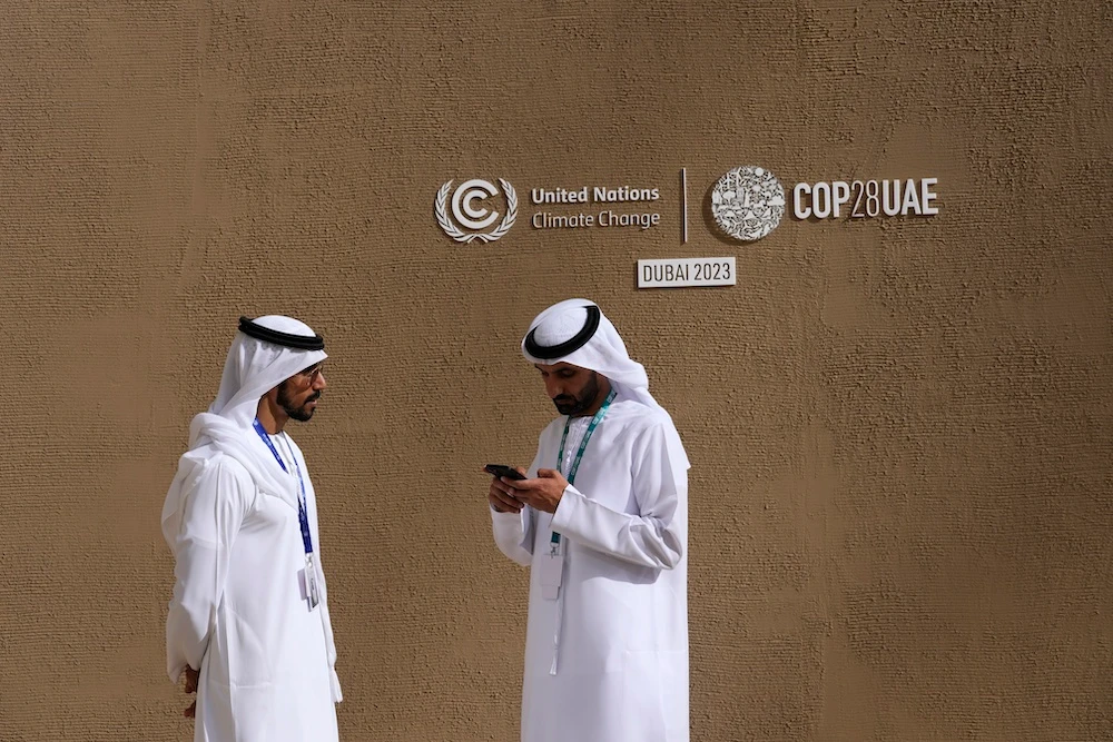 Delegates talk near a sign for the COP28 UN Climate Summit on Nov. 30, 2023 in Dubai. (AP)