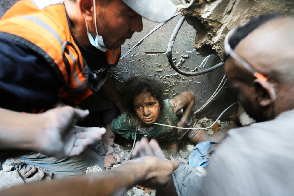 Palestinians try to pull a girl out of the rubble of a building that was destroyed by Israeli airstrikes in Jabaliya refugee camp, northern Gaza Strip. (AP)