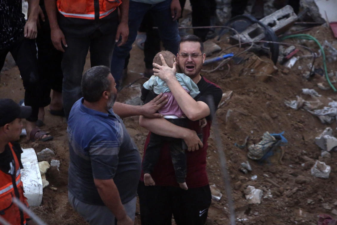 A Palestinian man cries while holding a dead child who was found under the rubble of a destroyed building following Israeli airstrikes in Nusseirat refugee camp, central Gaza. In just 25 days of war, more than 3,600 Palestinian children have been killed (AP)
