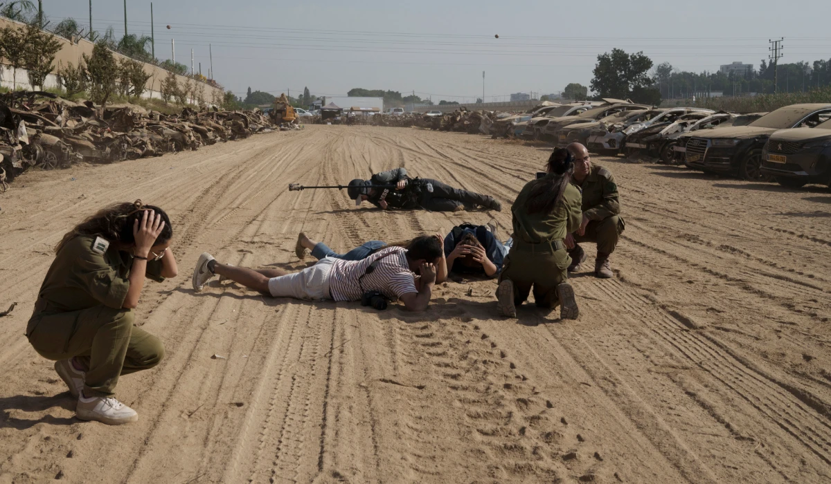 Israeli soldiers and journalists take cover as a siren warns of incoming rockets fired from the Gaza Strip in an area where hundreds of destroyed vehicles are kept that were damaged in the bloody Oct. 7 cross-border attack by Hamas militants, in which hundreds of people were killed and 240 others were taken hostage, outside the town of Netivot, southern Israel, Sunday, Nov. 5, 2023. (AP)