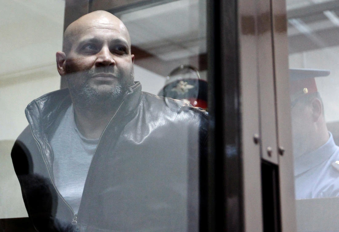 One of the defendants in the murder trial of Russian journalist and human rights activist Anna Politkovskaya, Sergei Khadzhikurbanov is escorted into a glass-walled cage before a court hearing in Moscow in 2013. (Reuters)