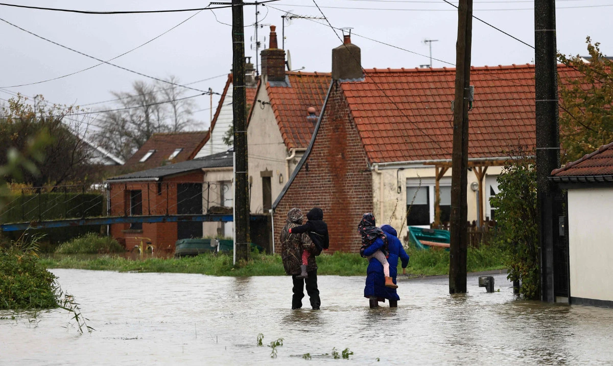 People walk in a flooded street in Le Doulac near Saint-Omer, northern France on November 14, 2023, as the Pas-de-Calais region was hit by torrential rains with a historic rise in water levels on November 7, 2023. (AFP)