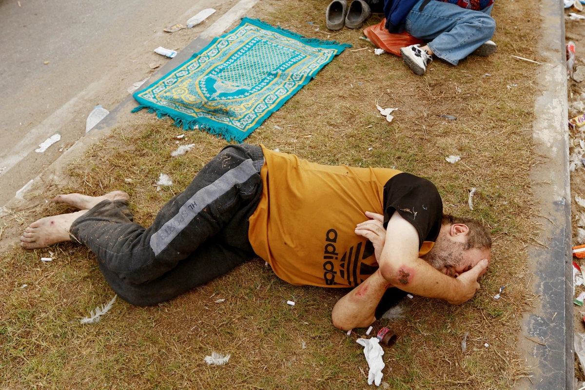 A Palestinian man, who was wounded in an Israeli strike and was staying at Al Shifa hospital, rests on the road as he flees from north Gaza to the south, as Israeli tanks roll deeper into the enclave, amid the ongoing conflict between Israel and Hamas, in the central Gaza Strip November 12, 2023. (REUTERS)