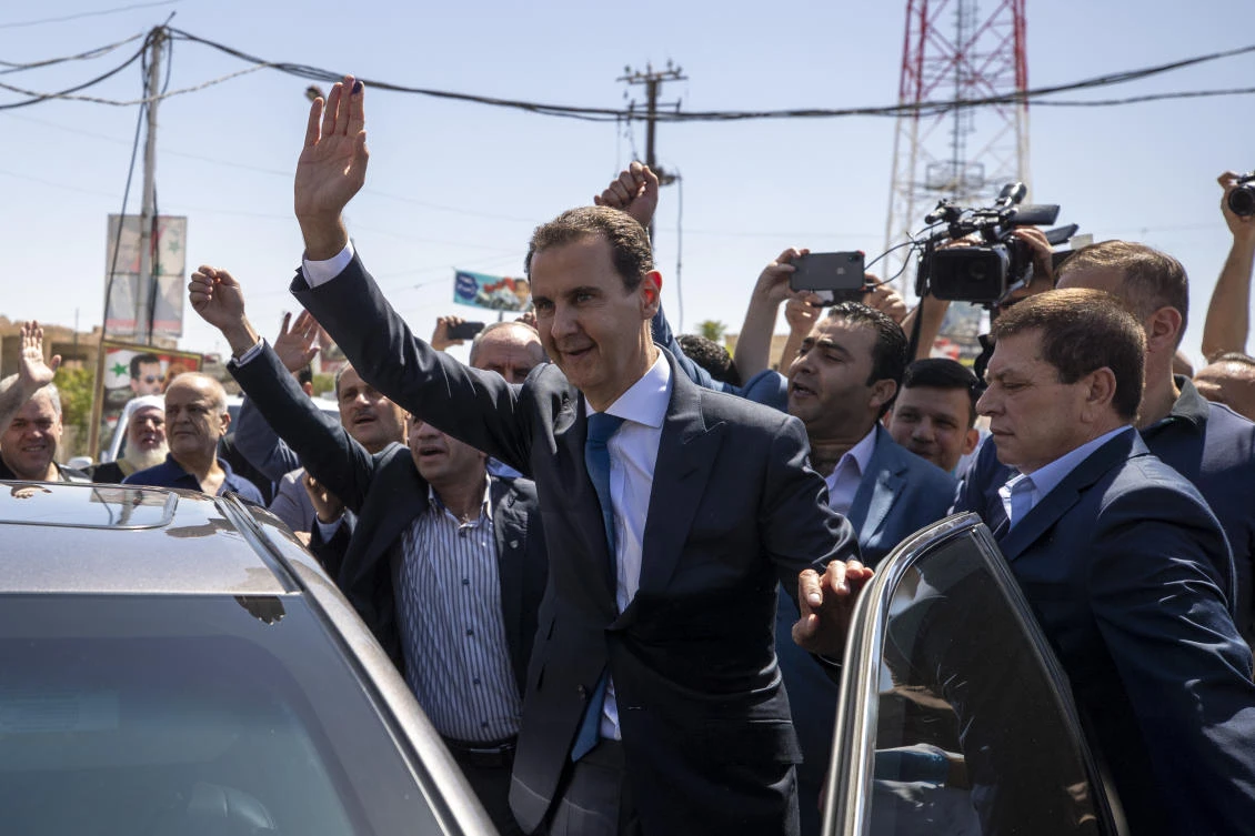 Syrian President Bashar Assad waves for his supporters at a polling station during the Presidential elections in the town of Douma, in the eastern Ghouta region, near the Syrian capital Damascus in May 2021. (AP/File)