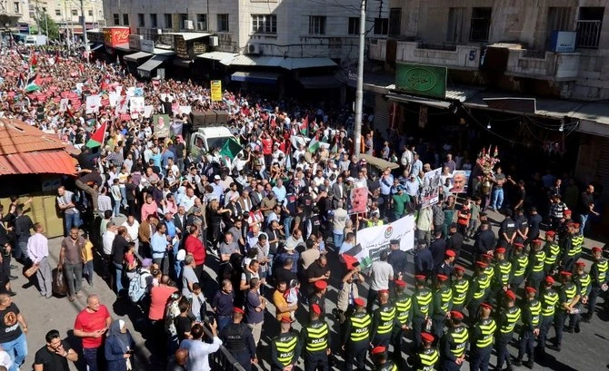 Police stand guard as demonstrators carry flags and banners during a protest in support of Palestinians in Gaza, Amman on Nov. 10, 2023. (Reuters)
