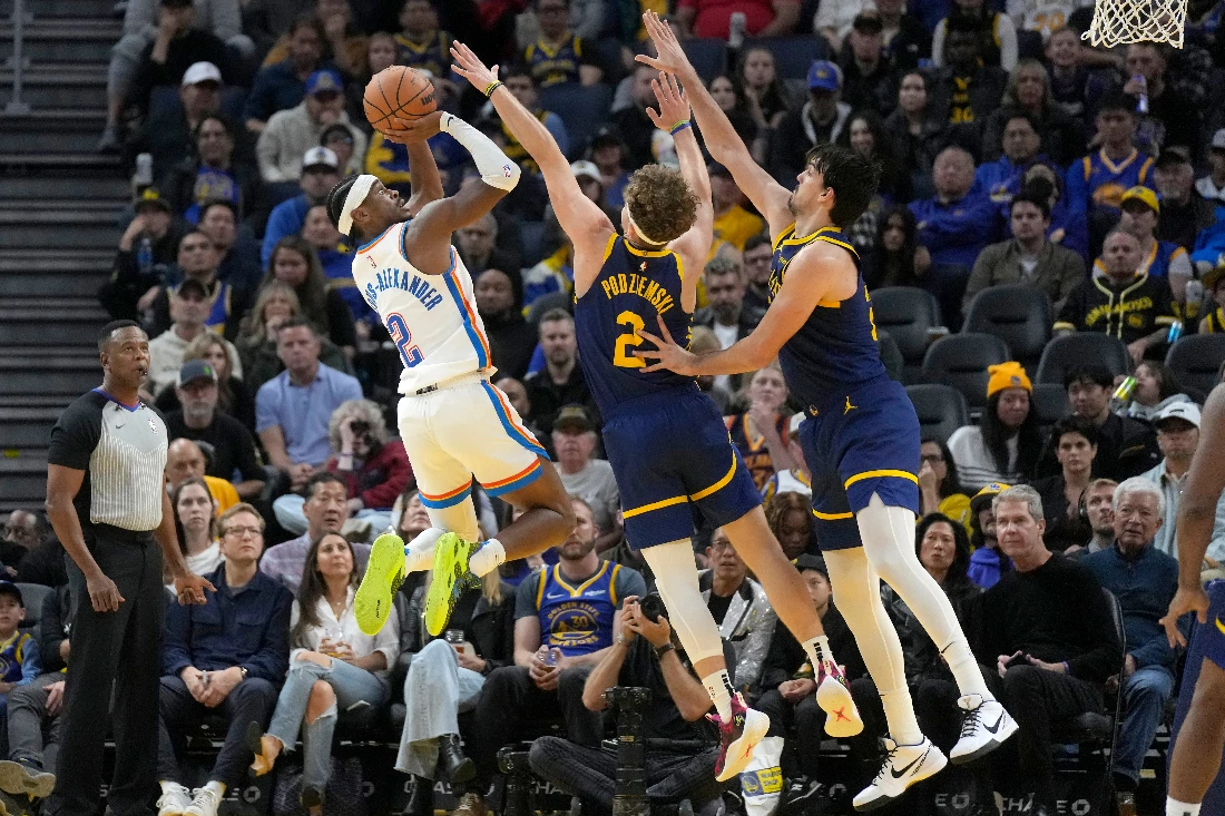 Oklahoma City Thunder guard Shai Gilgeous-Alexander, left, scores against Golden State Warriors guard Brandin Podziemski, middle, and forward Dario Saric during the second half of an NBA basketball game in San Francisco. (AP)