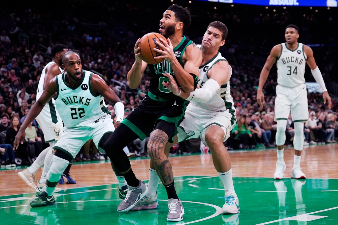 Boston Celtics forward Jayson Tatum drives to the basket against Milwaukee Bucks center Brook Lopez, right, and forward Khris Middleton (22) during the first half of NBA basketball game. (AP)