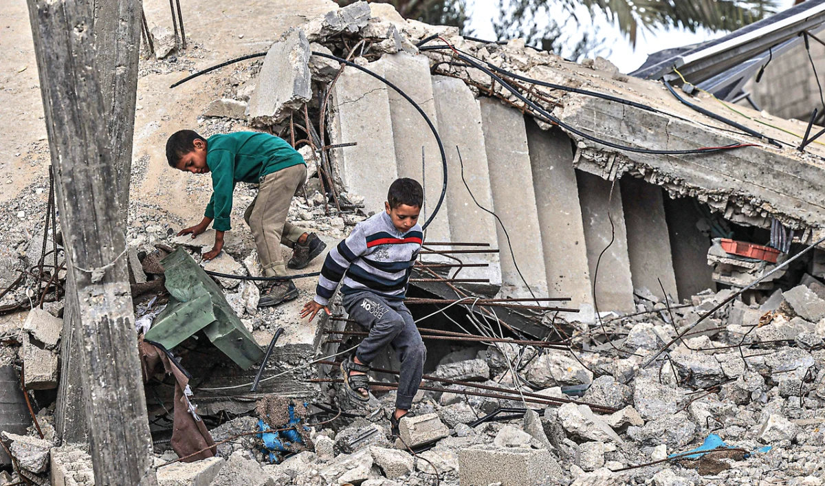 Palestinian boys walk amid the destruction caused by Israeli strikes in the village of Khuzaa, east of Khan Younis, on Monday. (AFP)