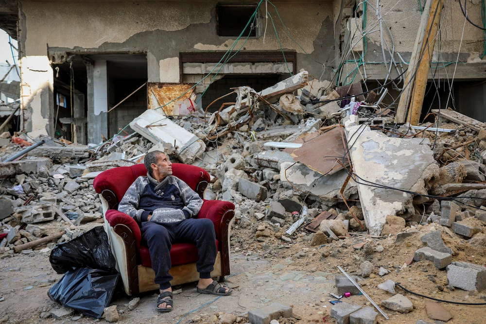 A Palestinian man sits in an armchair outside a destroyed building in Gaza City on Nov. 29, 2023, the sixth day of the temporary ceasefire between Hamas and Israel. (AP)