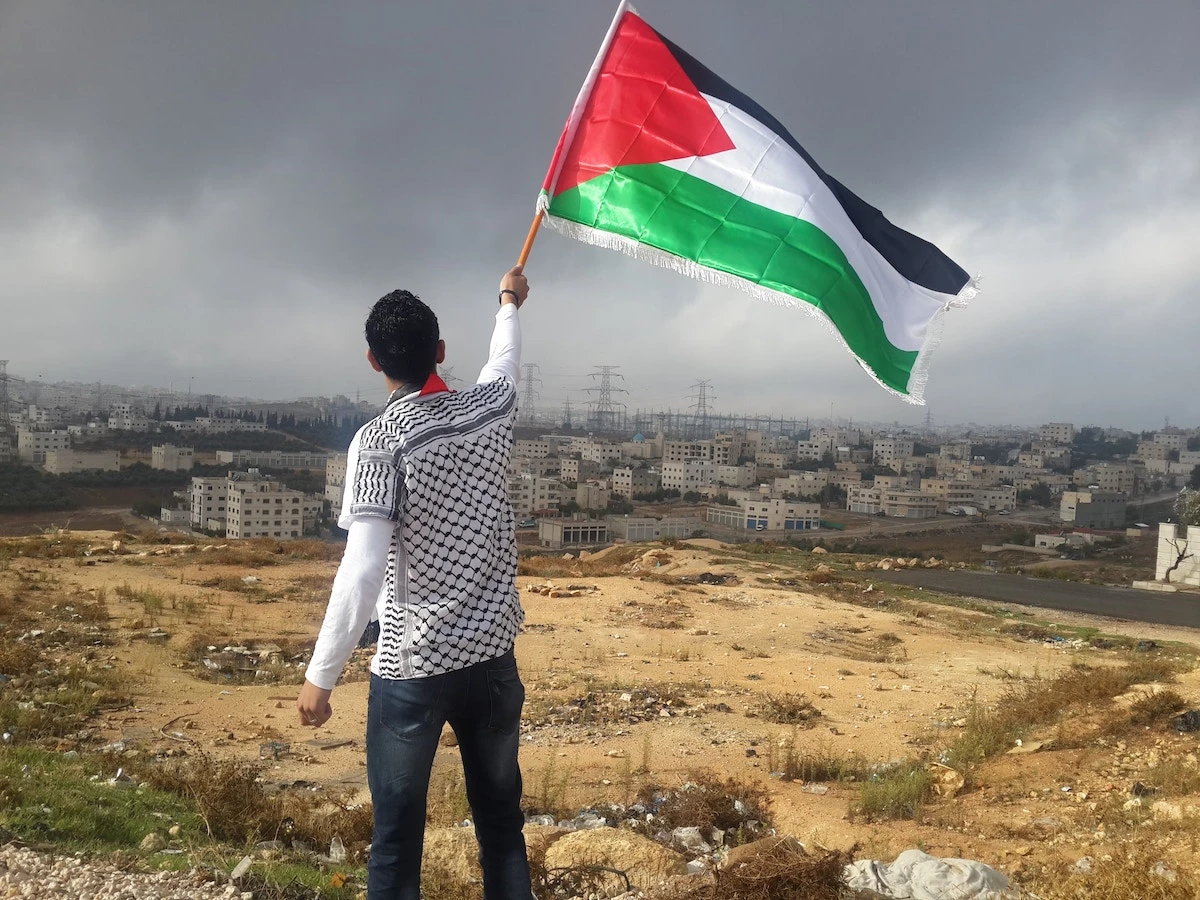 A senior CIA official posted a pro-Palestine image, showing a man waving a Palestinian flag on Facebook, last month. (Ahmed Abu Hameeda/Unsplash)