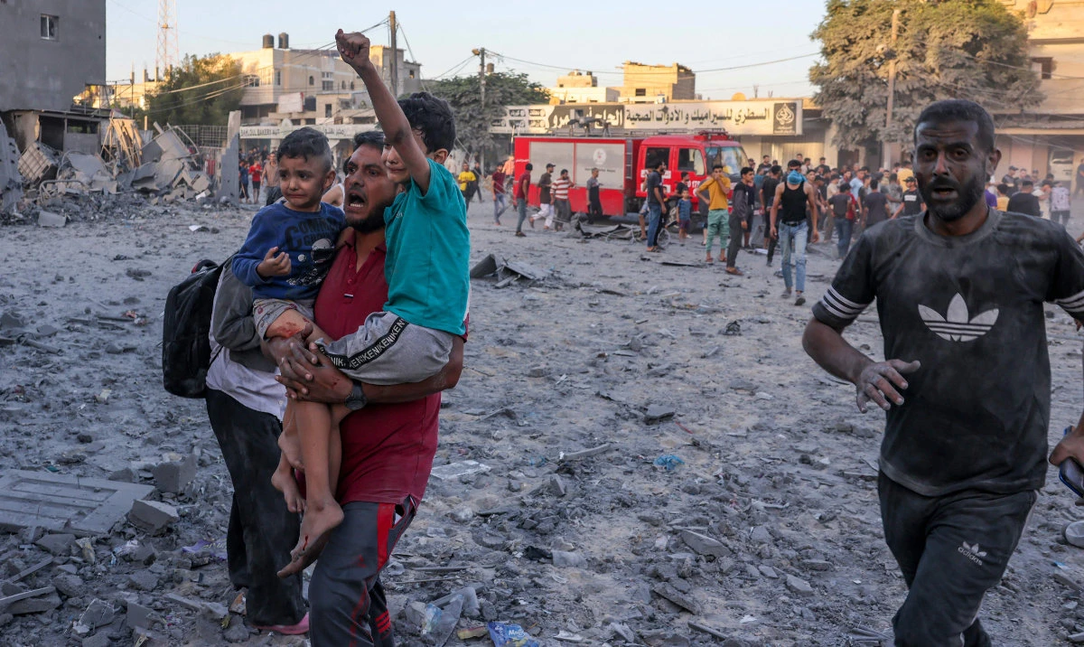 A wounded Palestinian man carries children following a strike in Rafah on the southern Gaza Strip on November 6, 2023. (AFP)