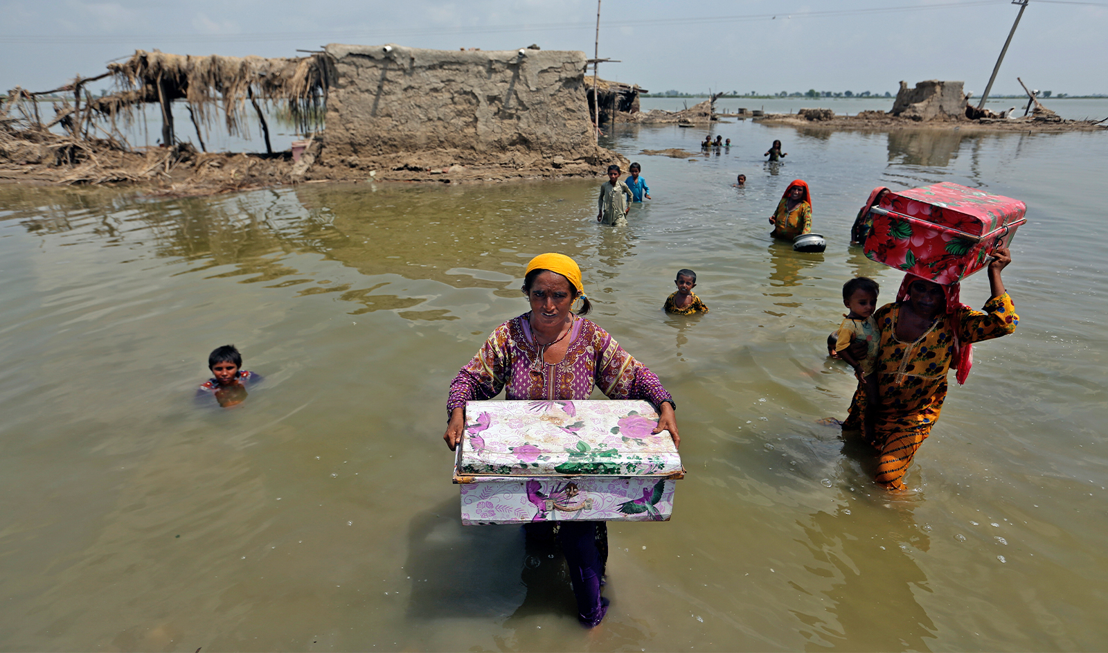Women carry belongings salvaged from their flooded home after monsoon rains in the Qambar Shahdadkot, Pakistan, on September 6, 2022. (AP/File)