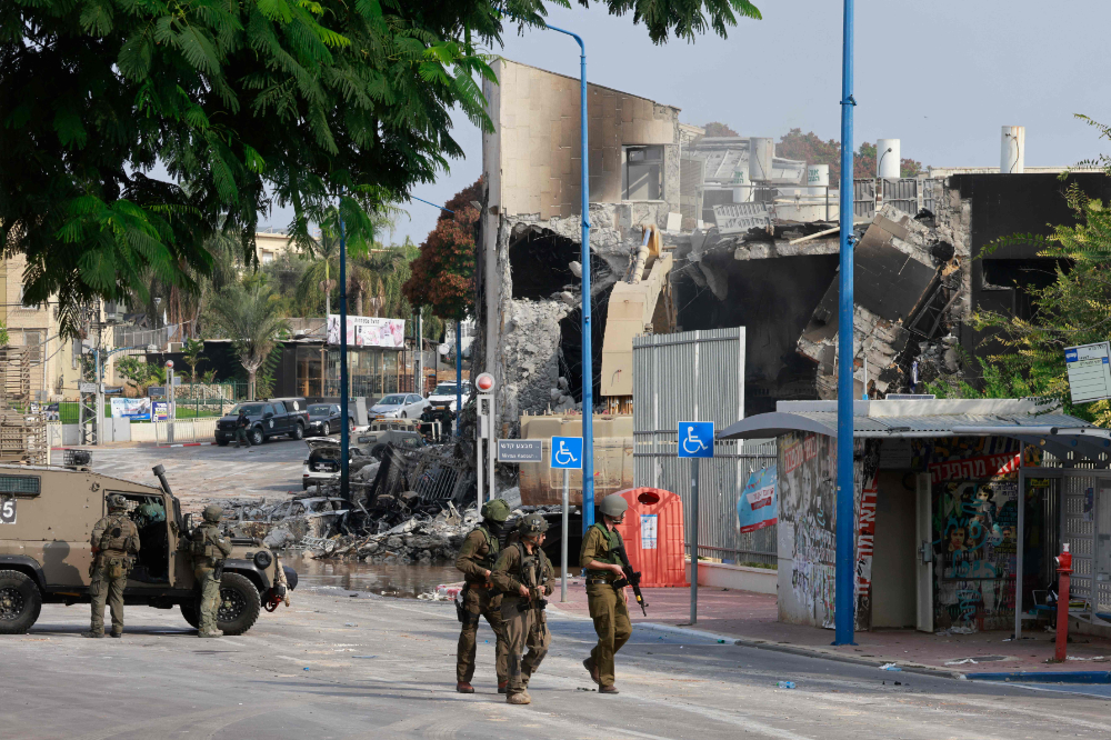 Israeli troops gather around a cordoned-off Israeli police station that was damaged during battles the previous day to dislodge Hamas militants who were stationed inside, on October 8, 2023. (AFP)