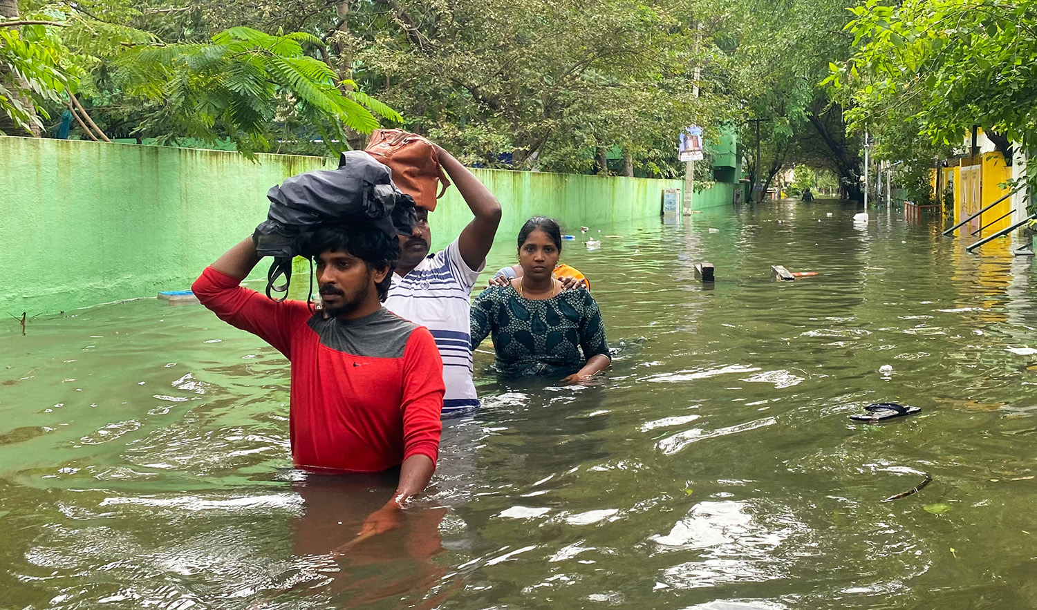 People wade along a flooded street in Chennai on December 5, 2023, following intense rains after Cyclone Michaung made a landfall. (AFP)