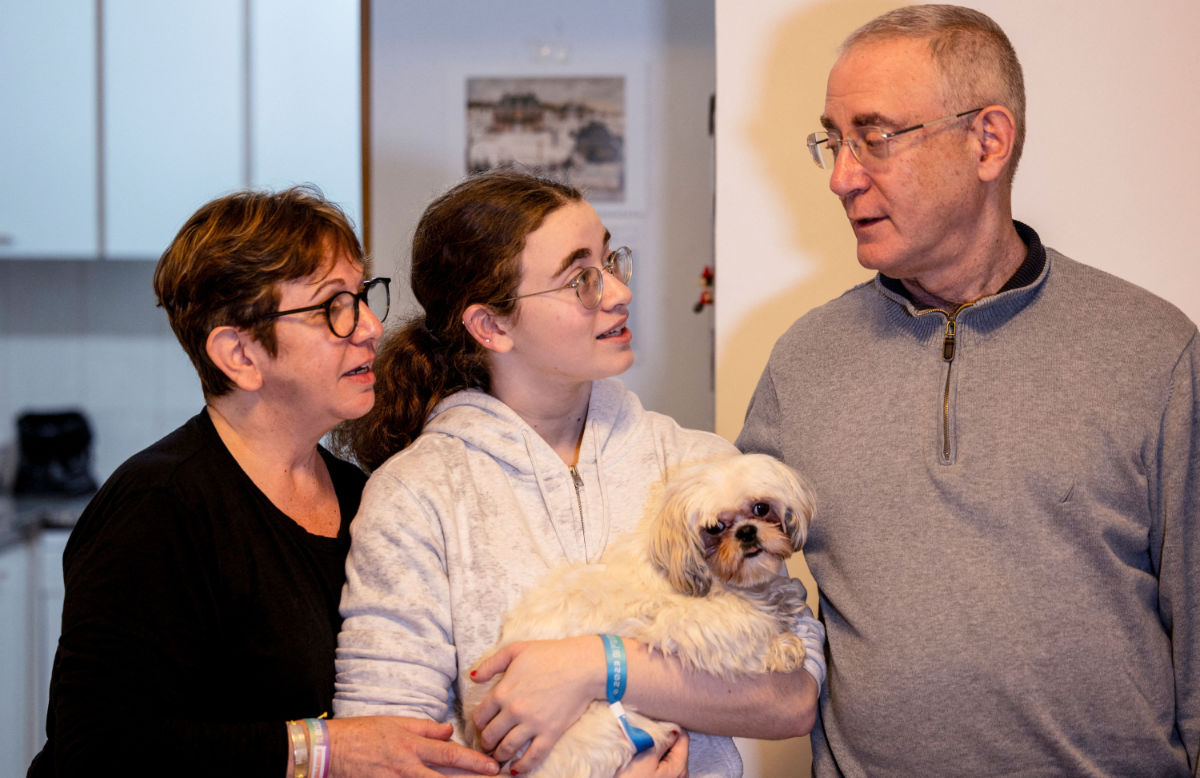 Mia Leimberg, 17, released from captivity after being taken hostage by the Palestinian Islamist group Hamas in the Gaza Strip with her mother Gabriela and her dog Bella, holds the dog in her arms as she stands with her mother and father, Moshe, at their home in Jerusalem, December 5, 2023. (REUTERS)