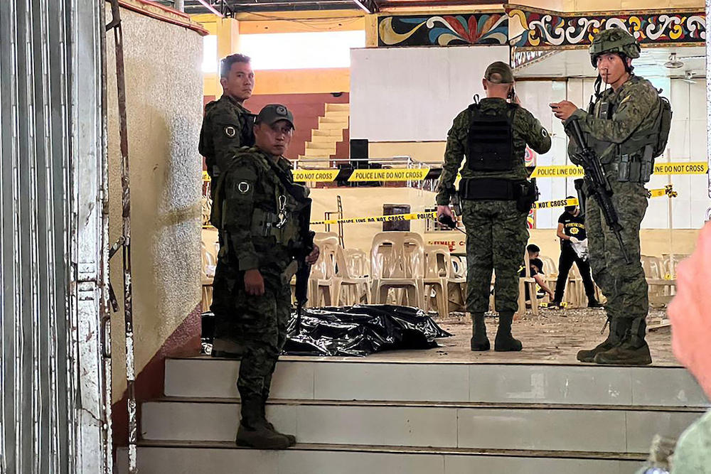 Military personnel stand guard at the entrance of a gymnasium while police investigators look for evidence after a bomb attack at Mindanao State University in Marawi, Lanao del Sur on Dec. 3, 2023. (AFP)