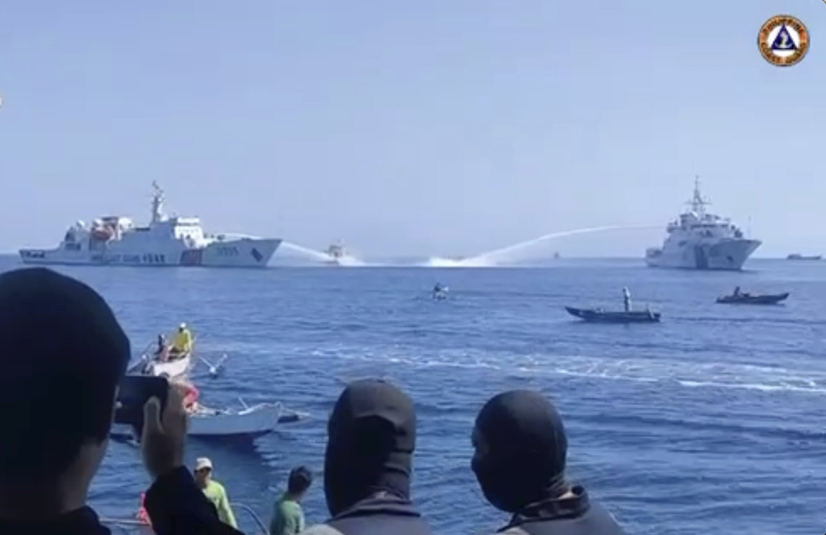 In this image taken from video provided by the Philippine Coast Guard, two Chinese Coast Guard ships aim their water cannons on a Philippine Bureau of Fisheries and Aquatic Resources (BFAR) vessel, center, as it approaches Scarborough Shoal in the disputed South China Sea on Saturday Dec. 9, 2023. (Philippine Coast Guard via AP)