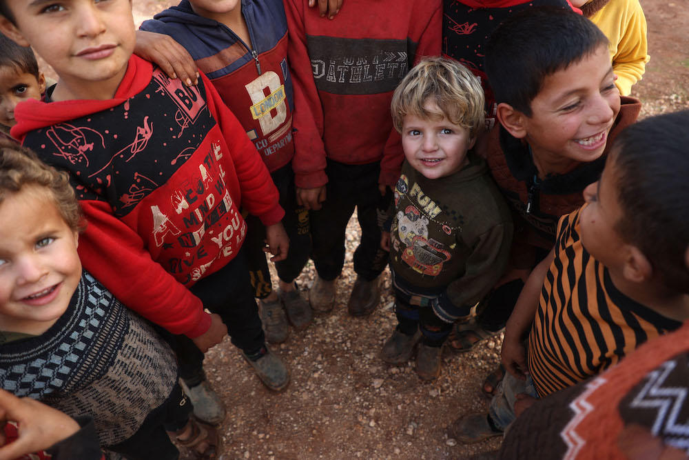 Syrian children stand as UN World Food Programme deliver relief packages to displaced Syrians on the outskirts of Idlib, in rebel-held northwestern Syria on Dec. 6, 2023. (AFP)