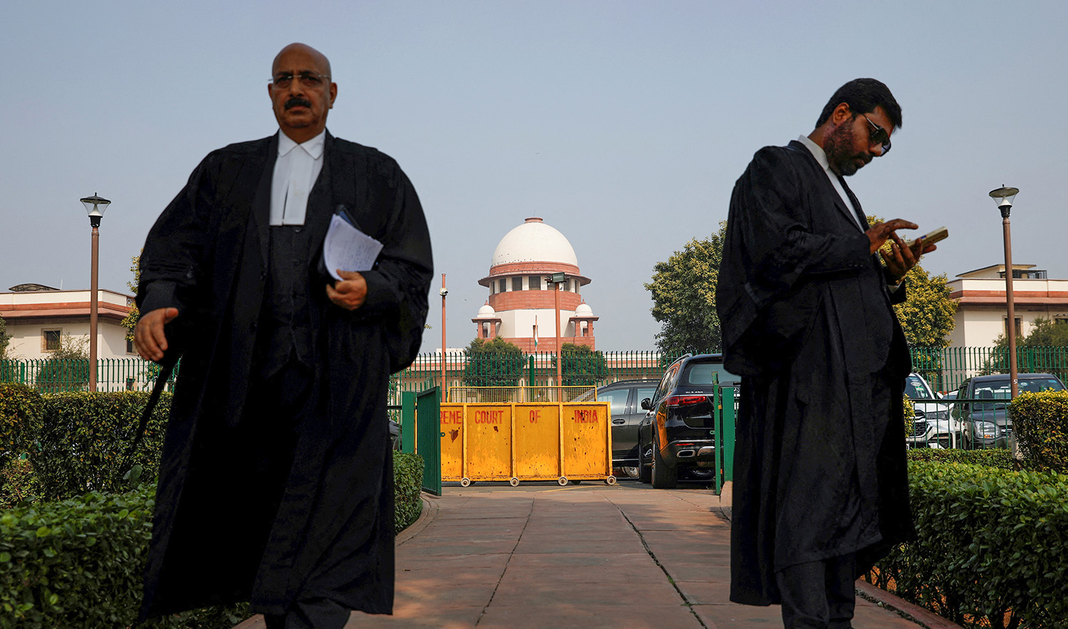 A lawyer looks into his mobile phone as another walks past, in front of India's Supreme Court in New Delhi on December 11, 2023. (REUTERS)