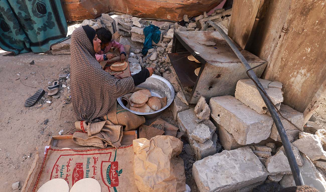 A Palestinian woman bakes bread inside a damaged house in Rafah on the southern Gaza Strip on December 11, 2023. (AFP)
