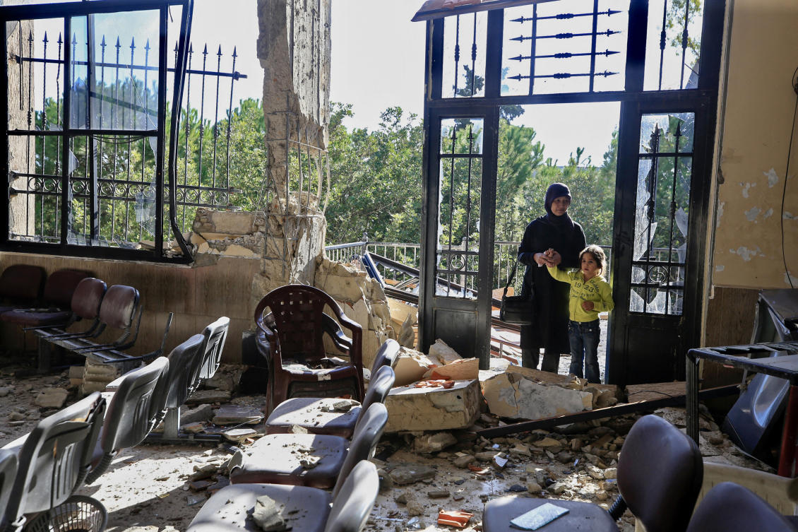 A woman and child stand at the entrance of a damaged building in the southern Lebanese village of Mheibib following an Israeli strike on November 24, 2023. (File/AFP)