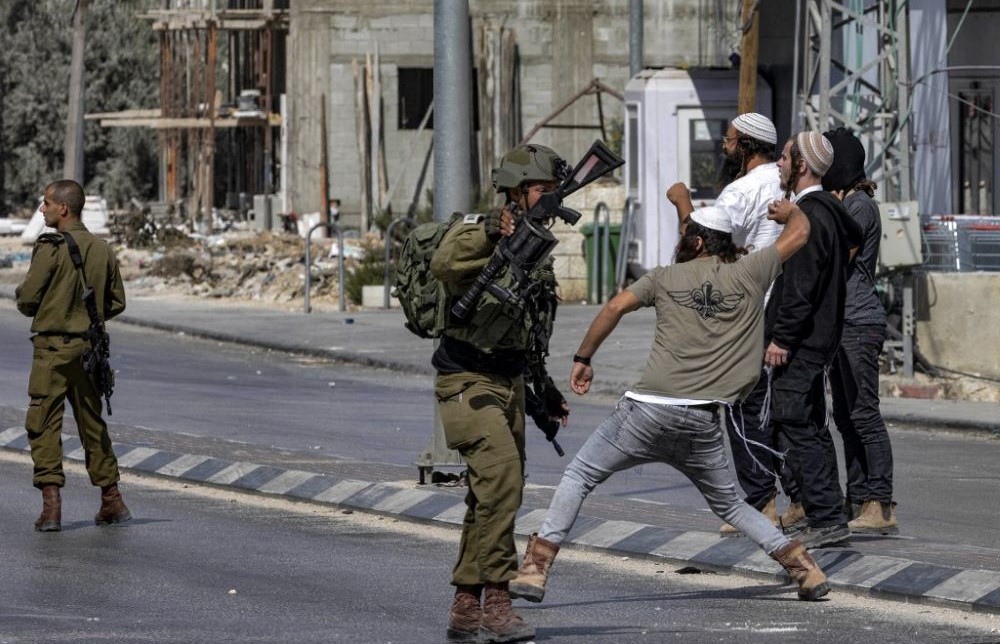 Israeli soldiers stand by as settlers throw stones at Palestinians during clashes in Huwara, occupied West Bank, Oct. 13, 2022. (AFP)