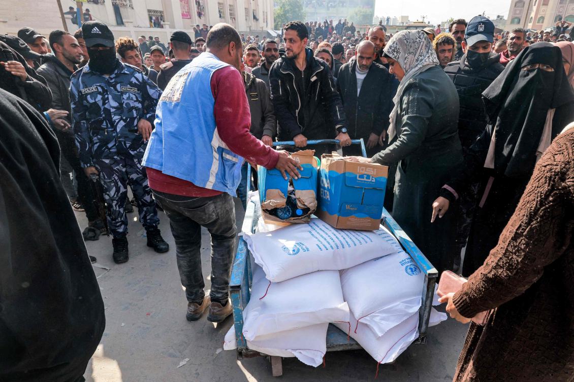 Workers of the United Nations Relief and Works Agency for Palestine Refugees (UNRWA) hand out flour rations and other supplies to people at an UNRWA warehouse in Rafah in the southern Gaza Strip, amid continuing battles between Israel and the militant group Hamas. (AFP)