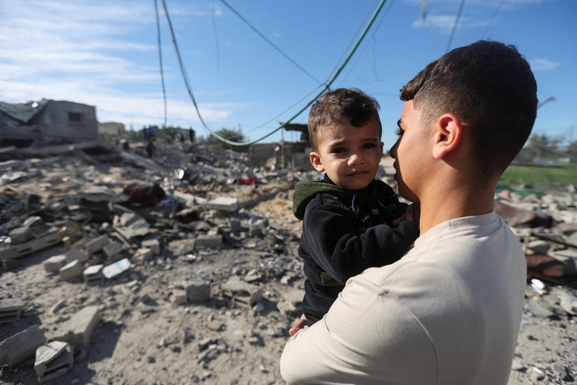 A Palestinian holds a child as they look on at the site of an Israeli strike on a house, amid the ongoing conflict between Israel and the Palestinian Islamist group Hamas, in Rafah, in the southern Gaza Strip. (Reuters)