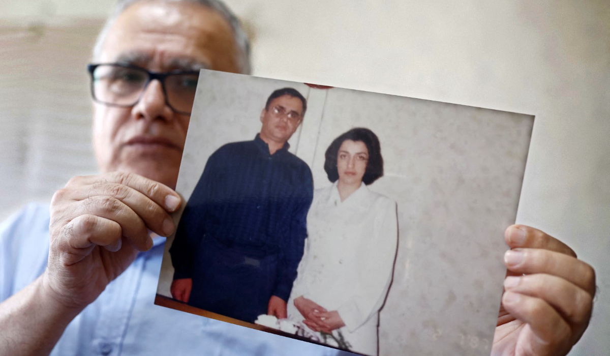 Taghi Ramahi, husband of Narges Mohammadi, poses with a photo of himself and his wife. (Reuters)