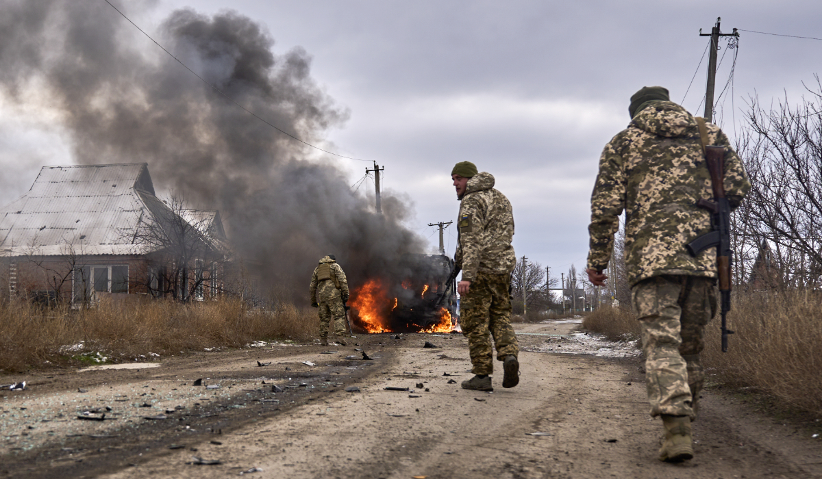 In this photo provided by the Ukrainian 10th Mountain Assault Brigade "Edelweiss", Ukrainian soldiers pass by a volunteer bus burning after a Russian drone hit it near Bakhmut, Donetsk region, Ukraine, Thursday, Nov. 23, 2023. (AP)