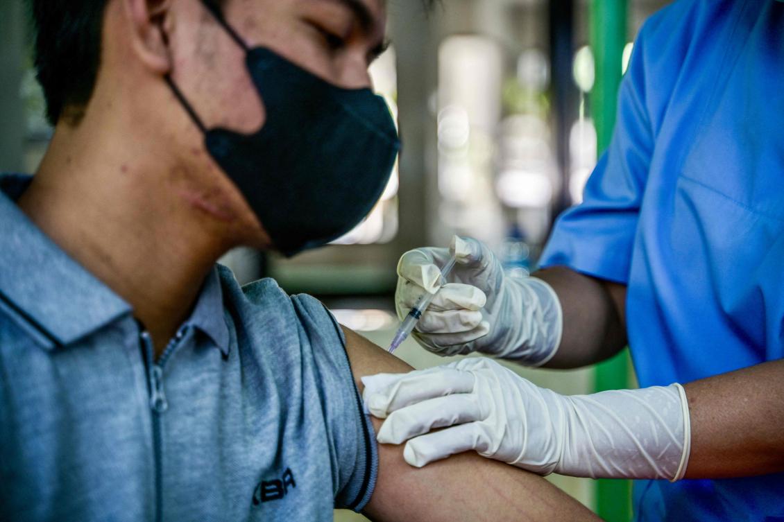 A health worker injects a man with a shot of the Inavac vaccine for Covid-19 at the Jakarta provincial health office on Dec. 19, 2023. (AFP)