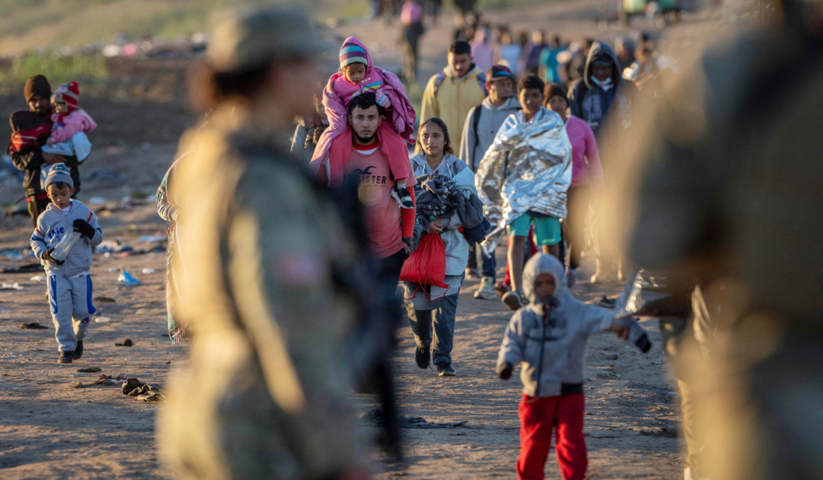 Texas National Guard soldiers observe as thousands of immigrants walk towards a U.S. Border Patrol transit center on December 19, 2023 in Eagle Pass, Texas. (AFP)